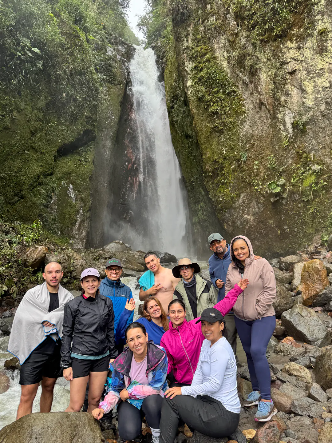 Grupo de caminantes celebrando frente a una cascada de montaña