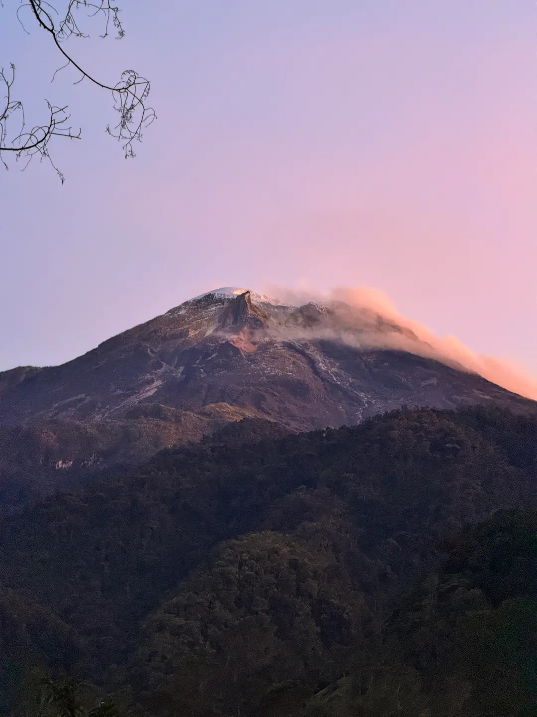 Volcán al atardecer con nubes encendidas de naranja