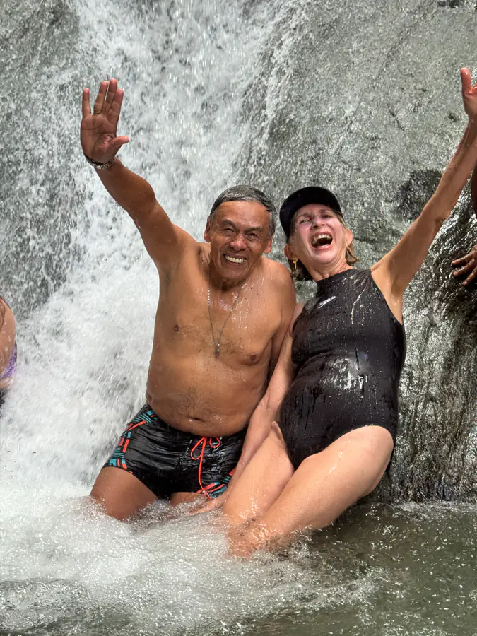 Pareja celebrando con los brazos en alto bajo una cascada